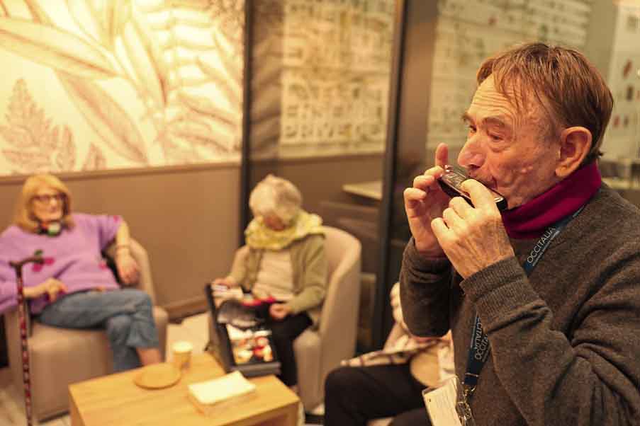 Michel, résident de l'Orangerie, joue à l'harmonica